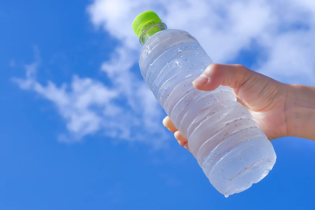 青空の中ペッドボトルの水を手にもつ