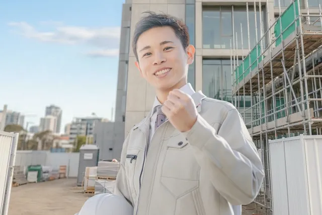 ガッツポーズをする作業着の若者
