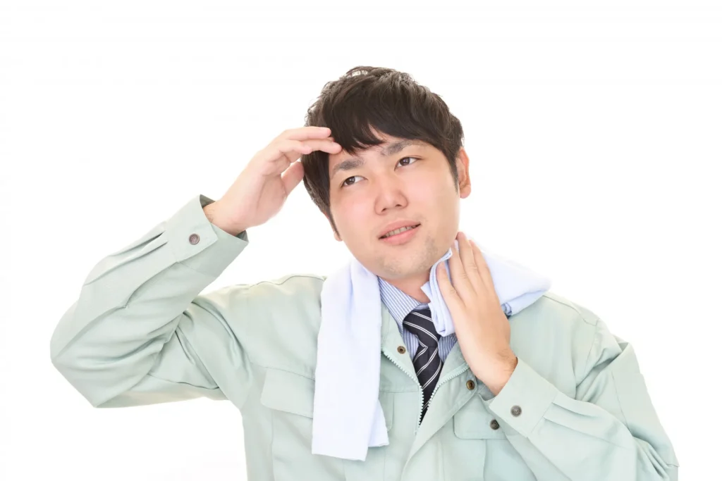 汗を拭いている作業員の男性